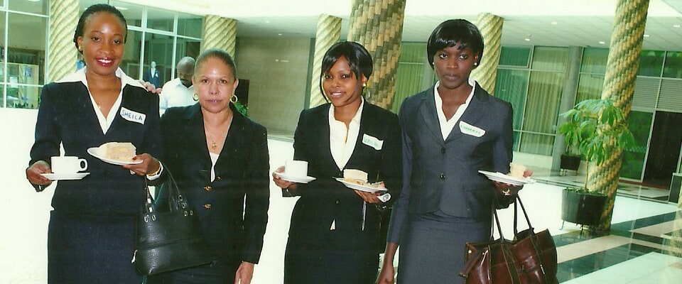 Four hospitality staff in black and white uniforms