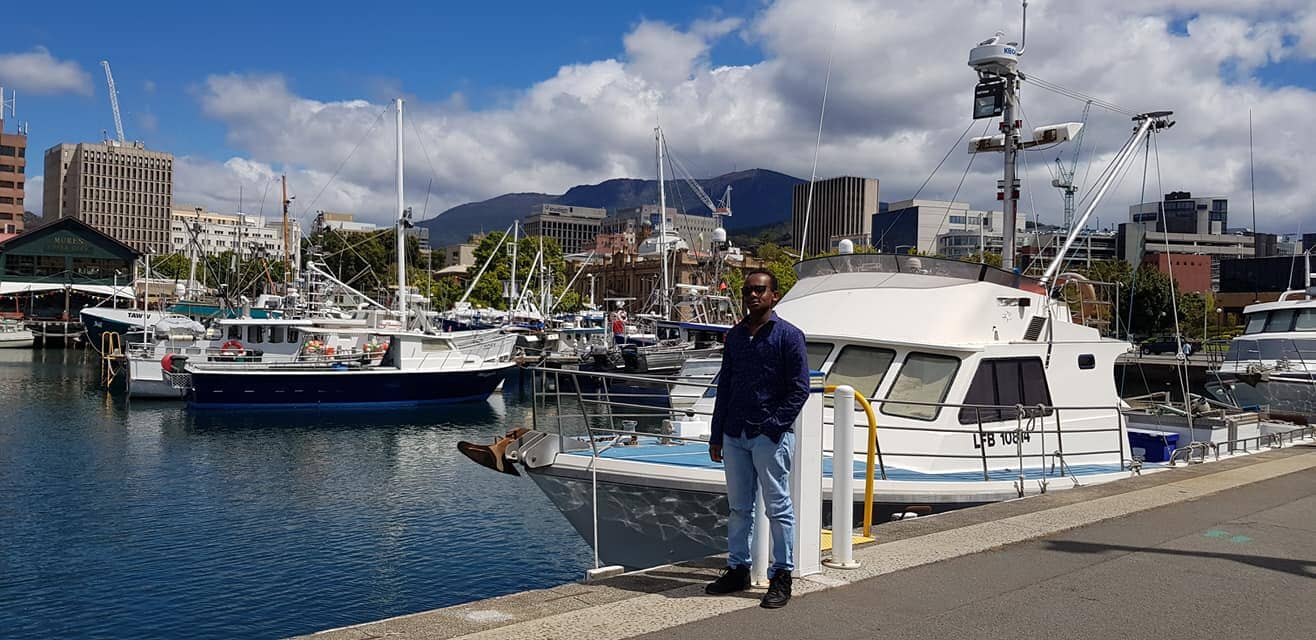 Person standing beside boats in a harbour